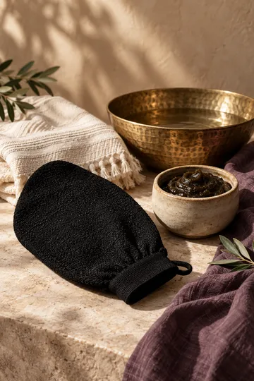 Moroccan bath mitt, black soap and towel — conceptual still life